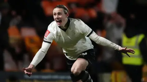 Ben Waine runs with his mouth open and his arms outstretched in celebration after scoring