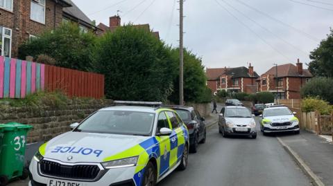 Two police cars parked on Costock Avenue in Sherwood, Nottingham, a residential street with houses on either side.