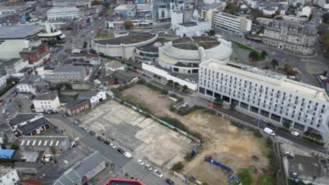 Ariel shot of the building site between Bath Street and Martin Street in Millbay, Plymouth. There are buildings around the area, and an empty space at the centre, which is the building site.