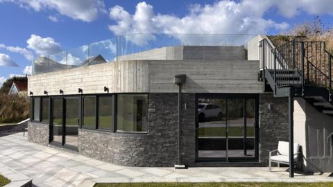 Grey building with black window frames and black stairs