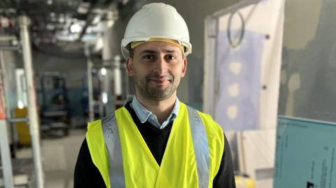 Miguel Vasconcelos standing in the new ward wearing a hard hat and high visibility vest