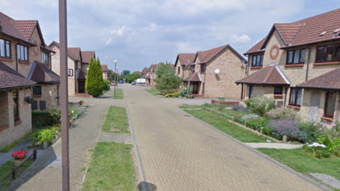 A residential street with modern two‑storey houses made of light brick. 