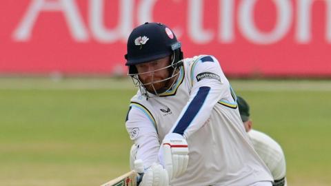 Jonny Bairstow, wearing a Yorkshire helmet, attempting a shot into the legside to a spinner, with the wicketkeeper stood behind the stumps