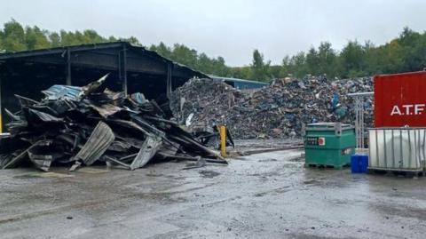 The remains of a building are piled on the left of a pile of rubbish.