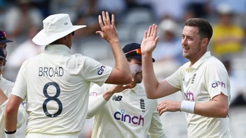Stuart Broad and Ollie Robinson high-five each other while playing for England