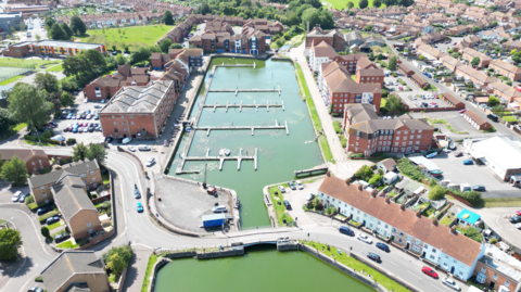 An aerial view of a dock and water, with residential buildings around it.