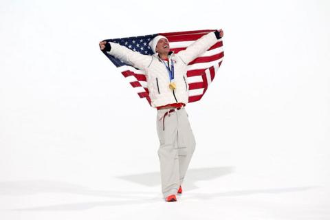 Athlete celebrates winning gold by holding the US flag