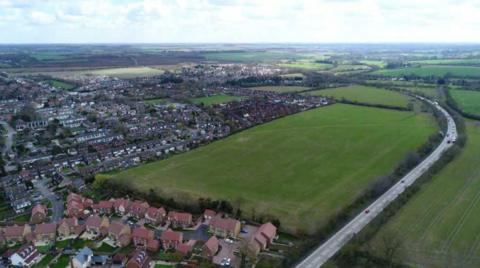 Aerial view of East of A10 site, a large green field between a major road and housing developments