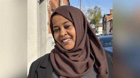 Fartun Ismail wearing a brown hijab and black suit jacket standing in a street.