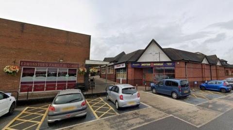 The Maltings shopping centre, in Uttoxeter, made up of a number of single-storey buildings with a car park and pedestrian walkway between the buildings.