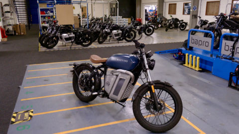 A blue and grey electric motorcycle on a factory floor