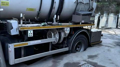 Lorry wheels stuck in a collapsed pavement