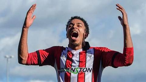 Lincoln City striker Alfie Lloyd celebrates with arms raised