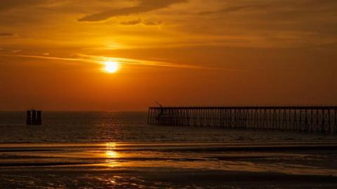 An orange sunset over the pier in Ramsey