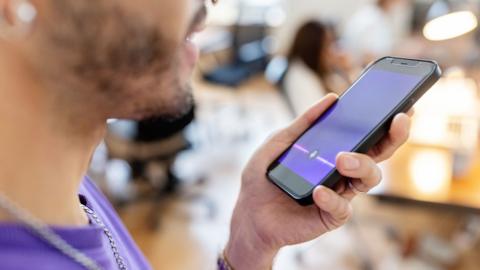 Close-up of man recording voice message on cellphone at office - stock photo