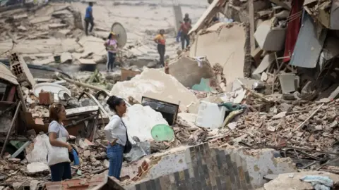 People look at the rubble of collapsed buildings in La Guaira, Venezuela