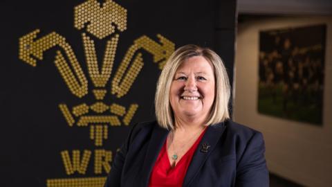 Nadine Griffiths stand in front of WRU badge
