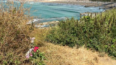 Flowers left on a cliff overlooking a beach