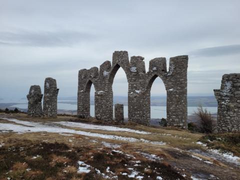 Ancient remains next to the coast with thick grey cloud above 