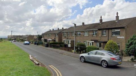 A Google streetview image of Hillcrest Drive in Bradford. A row of semi-detached houses run down the right hand side of the road.