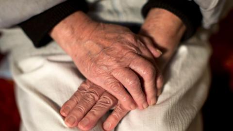 A picture of two hands, one on top of the other, on a white piece of clothing. The hands are the only part of the image fully in focus.