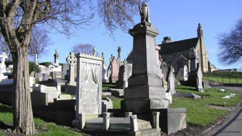 Large tombstones are shown in a cemetery