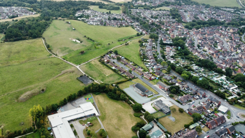 A drone shot of a housing estate next to fields - to illustrate land that could be used for housing. 
