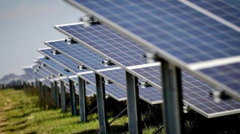 Series of blue solar farm panels located in a field.