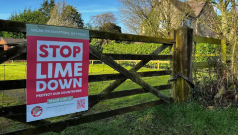 A sign which says Stop Lime Down attached to a wooden fence. The sign is a mixture of red and white
