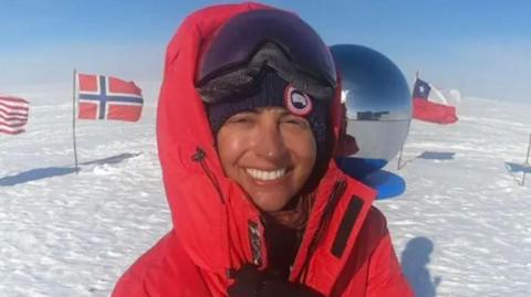 Capt Chandi in a hat and a big red coat in the South Pole.