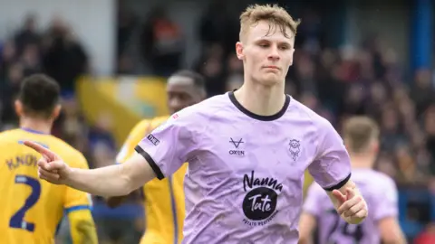 Rob Street, of Lincoln City, wearing the club's mauve away strip, celebrates after scoring from the penalty spot