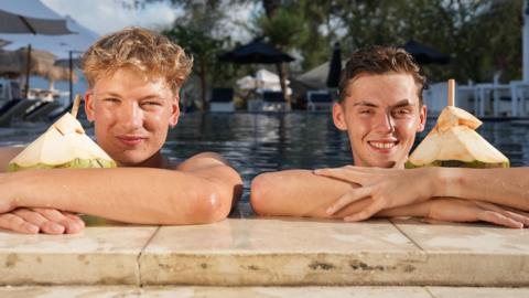 Alfie (right) and Owen pictured in a swimming pool with coconut drinks