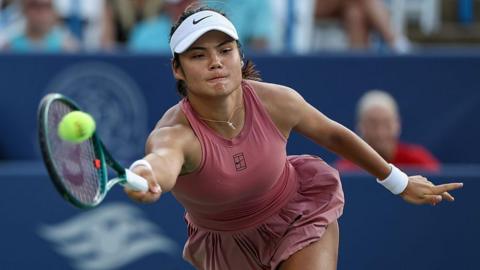 Emma Raducanu stretching to hit a tennis ball
