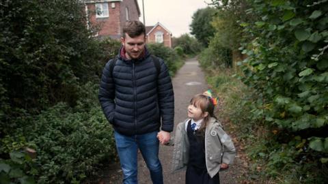 A father and daughter walking down the street