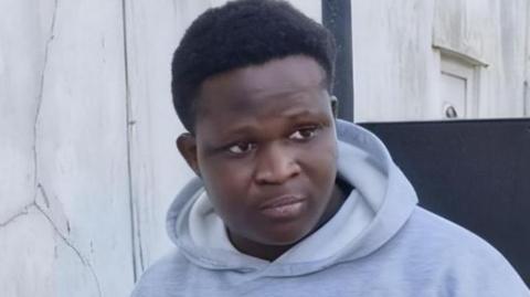 Miracle Oladoyinbo wearing a grey hoodie with white patterns on the front.