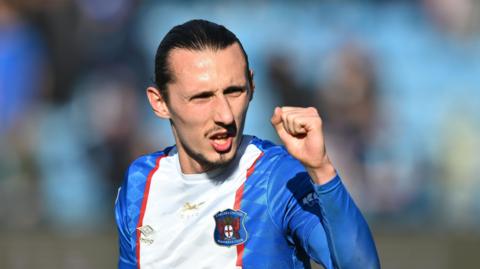 Callum Whelan with a clenched left-fist aimed in the direction of Carlisle supporters 