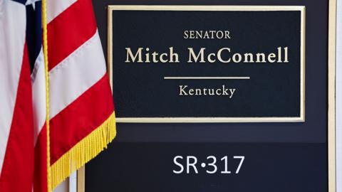 Mitch McConnell office sign, beside an american flag draped on a pole