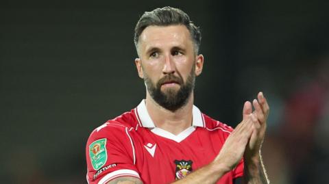 Ollie Palmer standing on the pitch and clapping his hands together at full-time