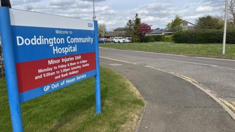 General image of the sign outside Doddington Community Hospital, which adds its opening times and that it is a minor injuries unit and GP out of hours service