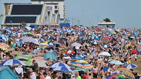 A crowded beach of umbrellas and people in bathing suits in Southend