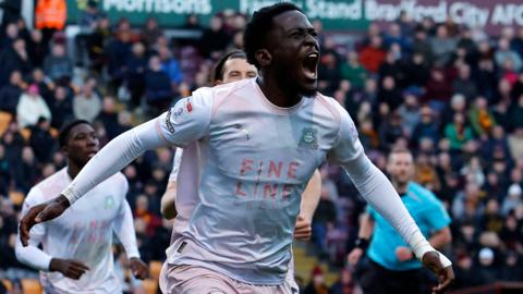 Brendan Wiredu run with his arms out wide and his eyes closed and mouth open in celebration after scoring a goal for Plymouth Argyle