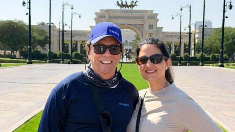 Krista Jucknath Hickman and her husband Mike, both in sunglasses, pose for a photo in front of a decorative archway in Dubai