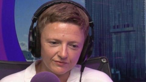 Bev Craig, wearing headphones, speaks into a microphone