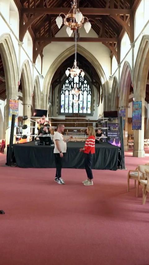 Man talks to woman in front of a wrestling ring in a church