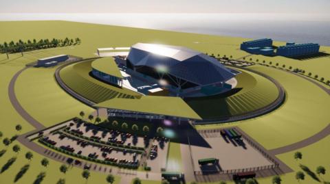 An computer generated artists impression of the what the site will look like. A silver building surrounded by green area, trees and a car park which sits in front of it.