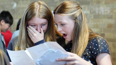 Two students collect their GCSE results and have an open-mouthed expression