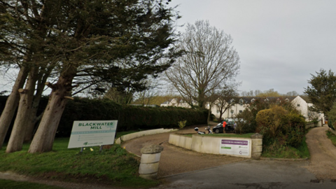 Exterior view of Blackwater Mill Residential ˿ - a white two-storey building at the end of a curved drive, with trees and a hedge to the left