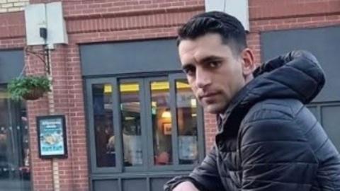 Madalin Ilnica, who has short dark hair and is wearing a dark jacket with a hood, which is down, looks at the camera.