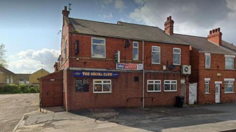 Moorends Social Club. A brick-built building with white window frames and a Sky Sports banner advertising live sport. The social club sign is in yellow letters against a blue background and there is a large car park to the side.