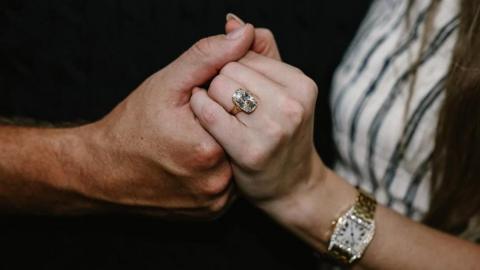 Kelce's hand holding Swift's hand, and her ring, which is big and sparkly, is visible on her ring finger. She also wears a gold watch with diamonds.